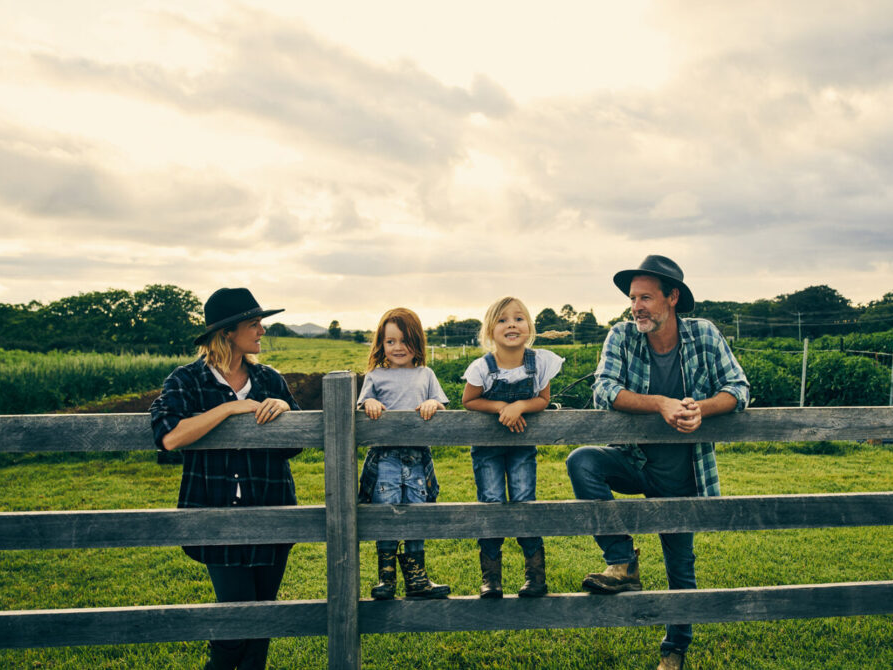 family posing on farm fence